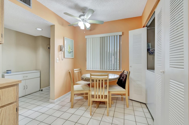 tiled dining room with ceiling fan and a textured ceiling