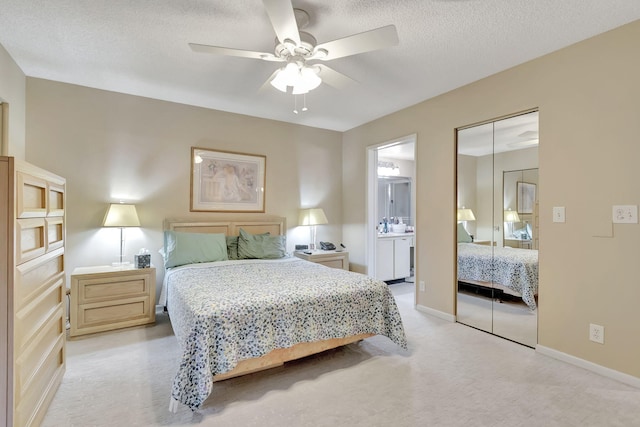 bedroom featuring ceiling fan, a textured ceiling, connected bathroom, light colored carpet, and a closet