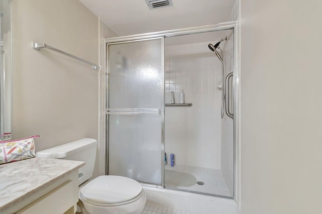 bathroom featuring tile patterned floors, vanity, a shower with shower door, and toilet