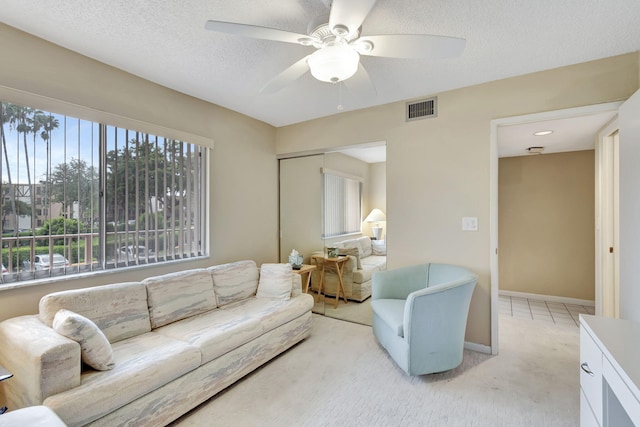 carpeted living room with a textured ceiling and ceiling fan