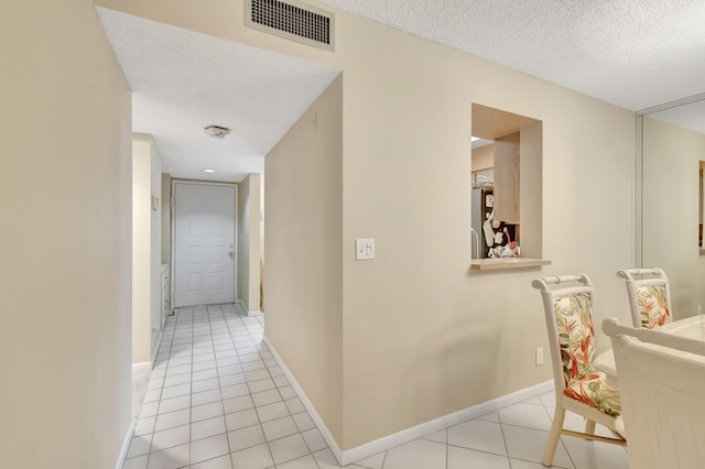 corridor featuring light tile patterned floors and a textured ceiling