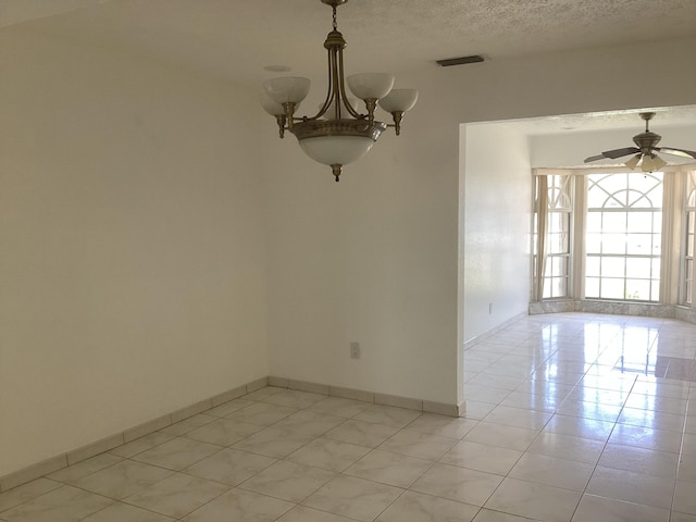 empty room with ceiling fan with notable chandelier, light tile floors, and a textured ceiling