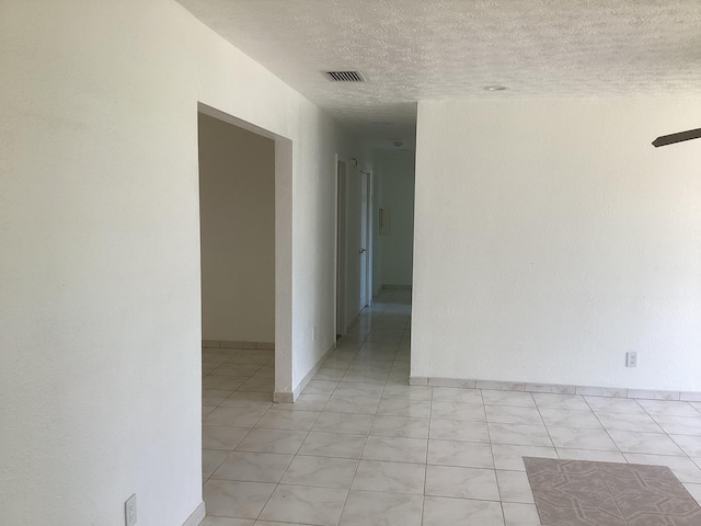 tiled empty room featuring a textured ceiling