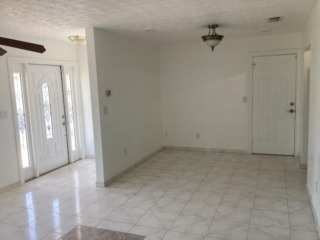 foyer with a textured ceiling, ceiling fan, and light tile floors