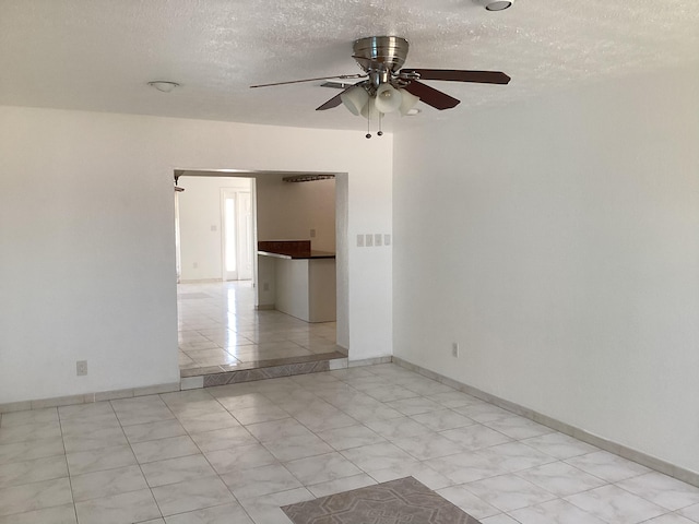 unfurnished room with a textured ceiling, ceiling fan, and light tile floors