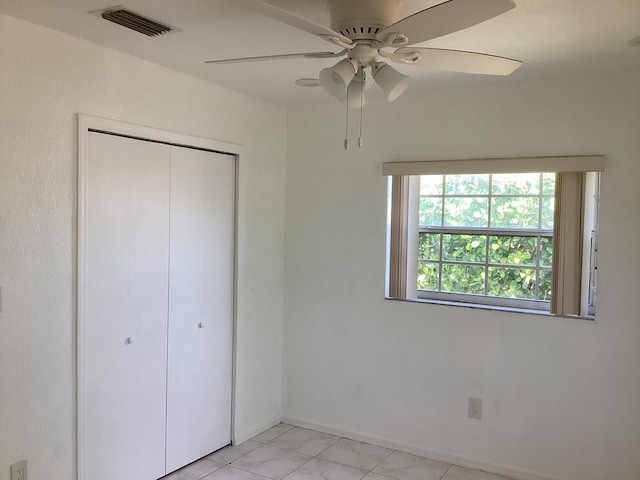 unfurnished bedroom with a closet, ceiling fan, and light tile flooring