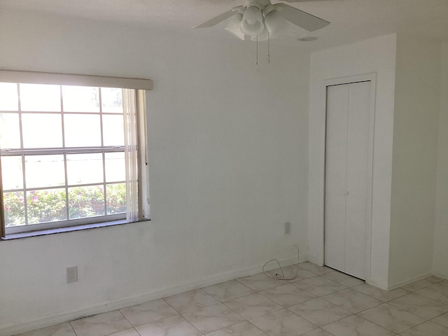 tiled spare room with ceiling fan