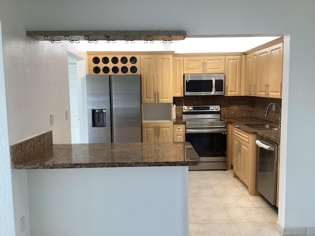 kitchen featuring light brown cabinets, stainless steel appliances, sink, tasteful backsplash, and dark stone counters