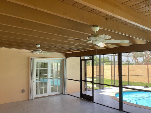 unfurnished sunroom with wooden ceiling, beam ceiling, ceiling fan, and french doors