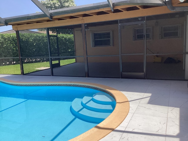 view of pool with glass enclosure and a patio