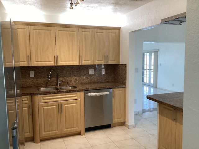 kitchen with stainless steel dishwasher, sink, light tile floors, and a textured ceiling