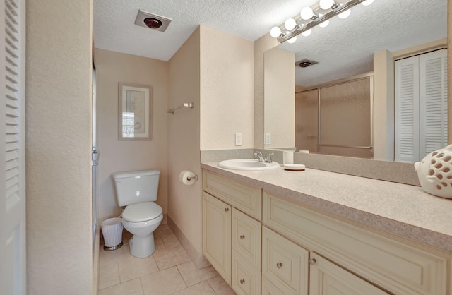 bathroom featuring a textured ceiling, tile flooring, toilet, and vanity with extensive cabinet space