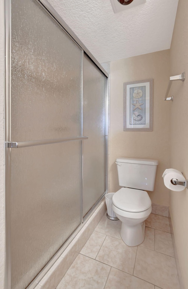 bathroom with a shower with door, tile flooring, a textured ceiling, and toilet