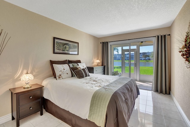 bedroom with a water view, a textured ceiling, light tile flooring, and access to outside