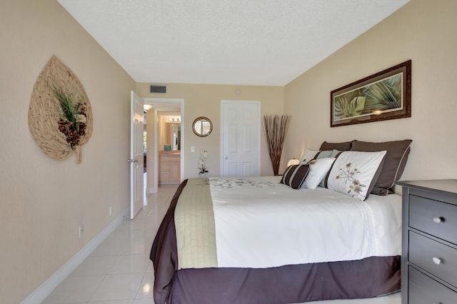 tiled bedroom featuring connected bathroom and a textured ceiling