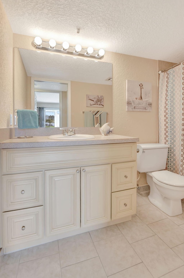 bathroom with tile floors, toilet, a textured ceiling, and vanity