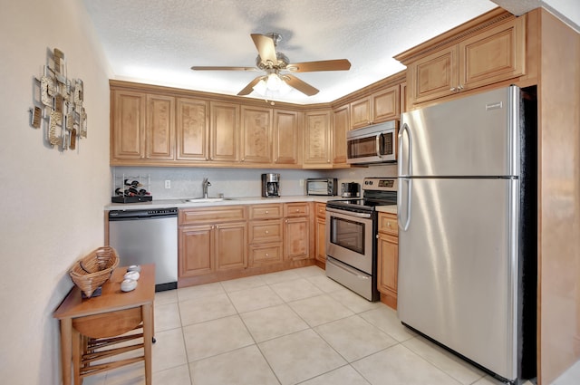 kitchen featuring light tile floors, appliances with stainless steel finishes, ceiling fan, and sink