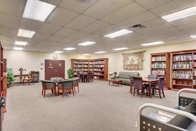 carpeted dining area with a paneled ceiling