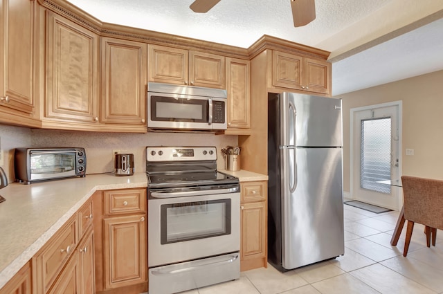 kitchen featuring a textured ceiling, ceiling fan, appliances with stainless steel finishes, and light tile floors