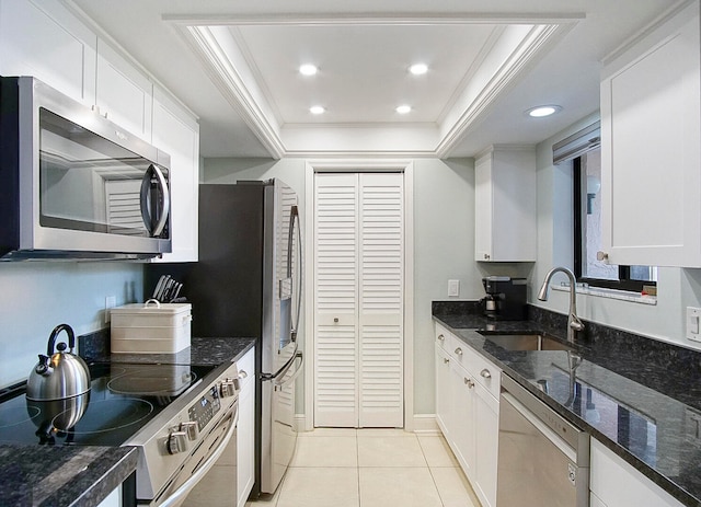 kitchen with white cabinets, a tray ceiling, appliances with stainless steel finishes, and sink