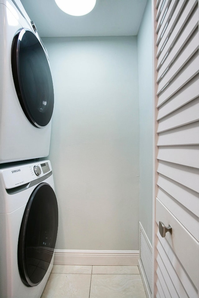 laundry area with light tile floors and stacked washer and clothes dryer