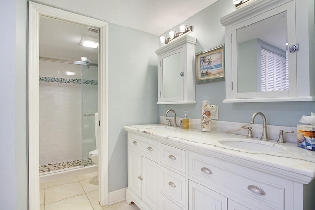 bathroom featuring toilet, dual vanity, a textured ceiling, tile floors, and a tile shower