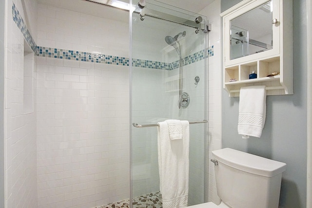 bathroom featuring toilet and a shower with shower door