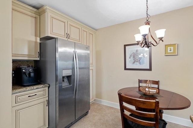 kitchen featuring stainless steel refrigerator with ice dispenser, decorative light fixtures, decorative backsplash, and cream cabinetry