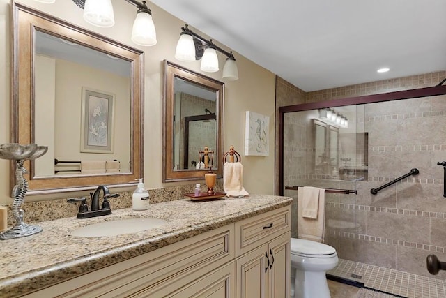 bathroom featuring a shower with shower door, vanity, and toilet