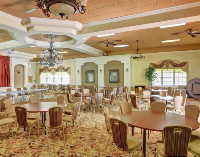 dining space with ornamental molding, ceiling fan with notable chandelier, and coffered ceiling