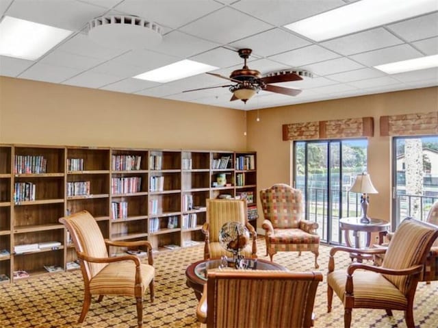 living area featuring ceiling fan, a paneled ceiling, and carpet flooring