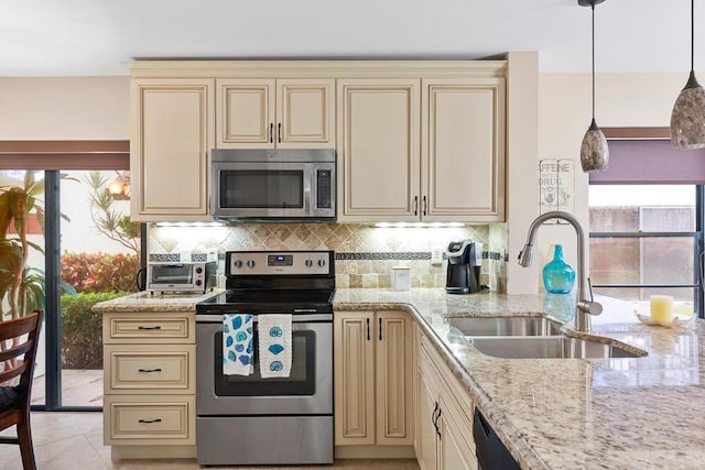 kitchen with decorative light fixtures, sink, stainless steel appliances, and cream cabinets