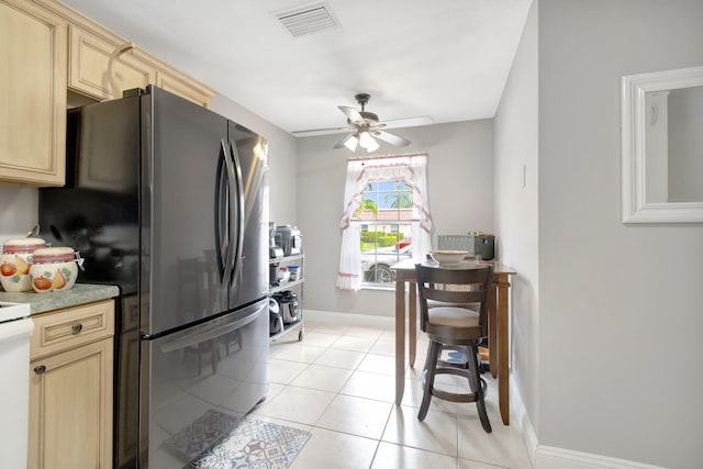 kitchen with light brown cabinets, ceiling fan, light tile floors, stainless steel fridge, and light stone countertops