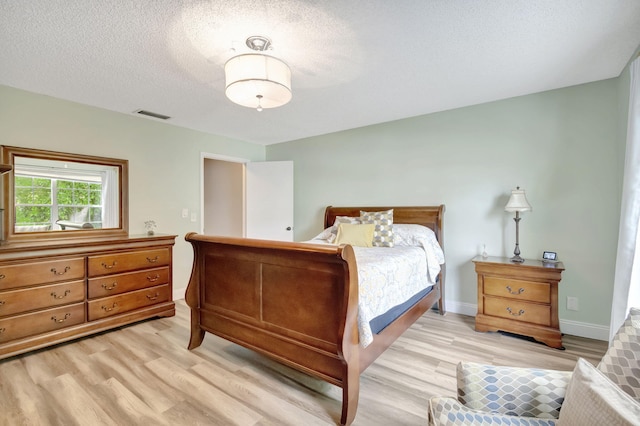 bedroom featuring light hardwood / wood-style flooring and a textured ceiling