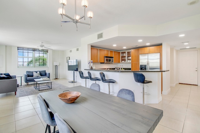 dining room featuring light tile floors and ceiling fan with notable chandelier