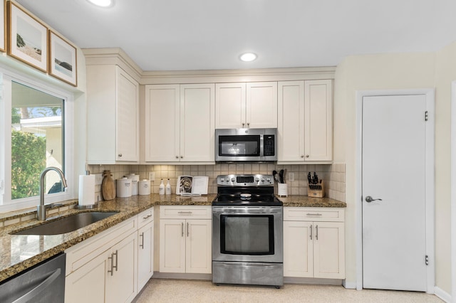 kitchen featuring dark stone countertops, a sink, stainless steel appliances, backsplash, and recessed lighting