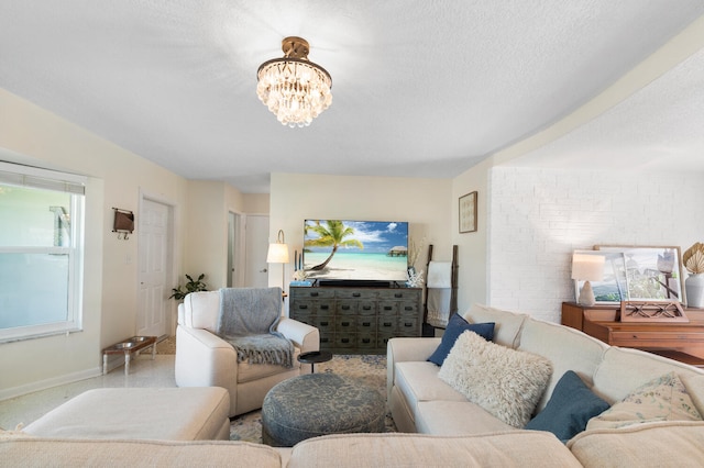 living room featuring a textured ceiling, baseboards, and an inviting chandelier