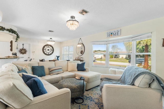 living area featuring a chandelier, visible vents, and a textured ceiling