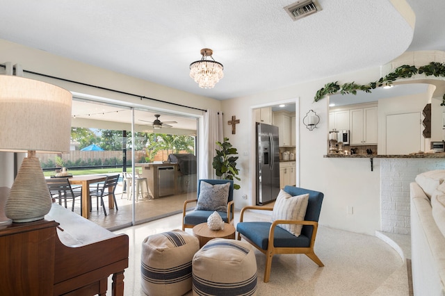 living area with visible vents, a notable chandelier, and a textured ceiling