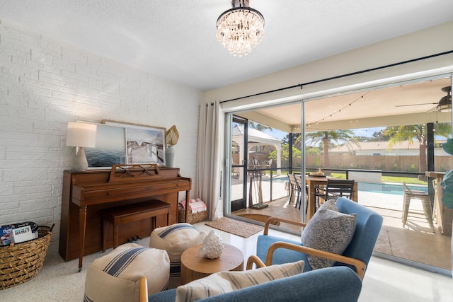 living area with a textured ceiling, ceiling fan with notable chandelier, and a sunroom