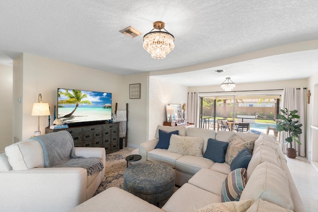 living area featuring a textured ceiling, visible vents, and an inviting chandelier