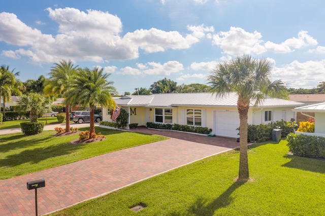 single story home with an attached garage, a front lawn, decorative driveway, and stucco siding