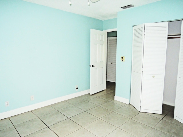 unfurnished bedroom featuring light tile floors and a closet