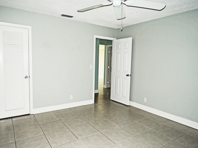 empty room featuring ceiling fan and tile floors