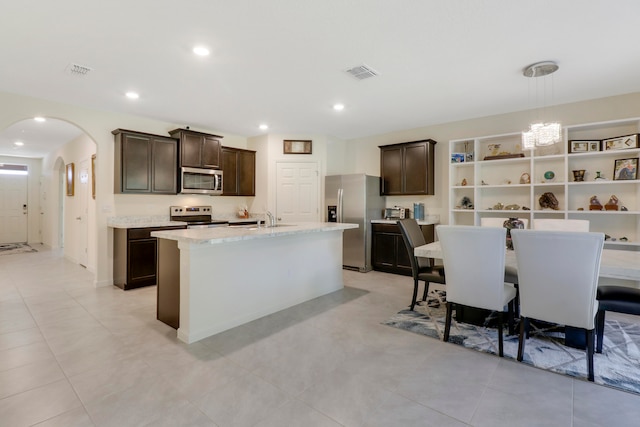 kitchen featuring a notable chandelier, a kitchen bar, pendant lighting, and a kitchen island with sink