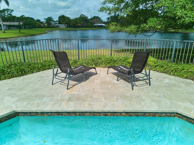 view of swimming pool with a patio, a yard, and a water view