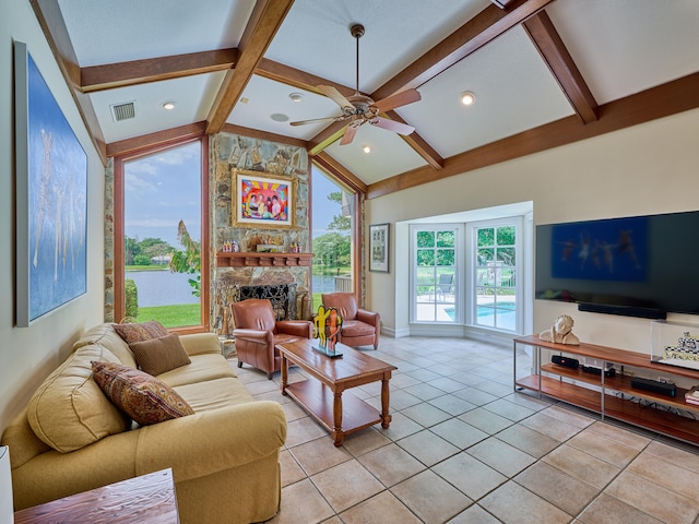 tiled living room featuring ceiling fan, vaulted ceiling with beams, and a stone fireplace