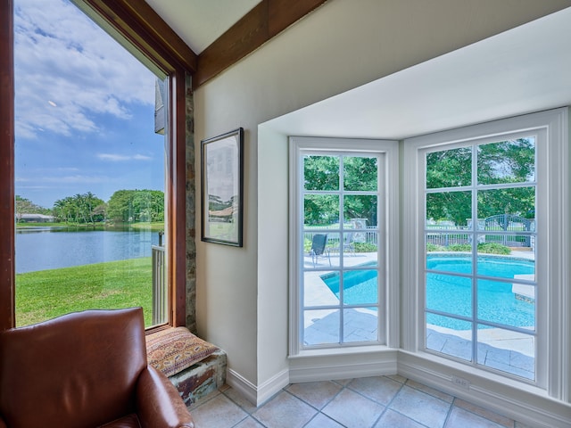 doorway with a water view, a wealth of natural light, and light tile floors