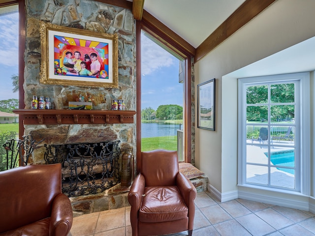 interior space featuring a water view, lofted ceiling, a wealth of natural light, and a stone fireplace