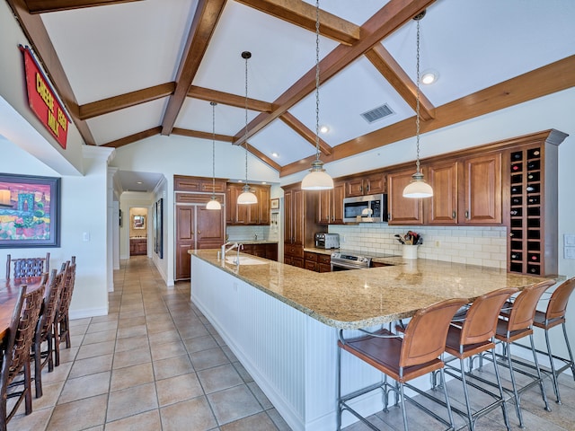 kitchen with a kitchen breakfast bar, decorative light fixtures, light stone countertops, backsplash, and stainless steel appliances